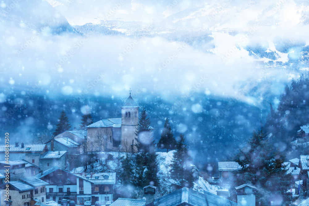 View of church in Champagny-en-Vanoise village in France during heavy snowfall at winter