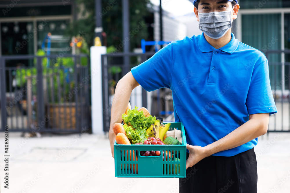 Asian delivery man blue uniform wearing medical face mask making grocery service giving fresh food t