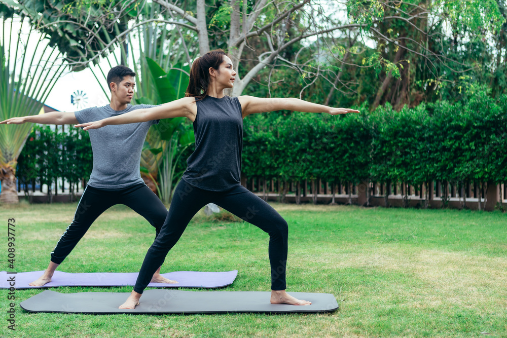 Young Asian couple man and woman practicing yoga in the garden. Summer morning