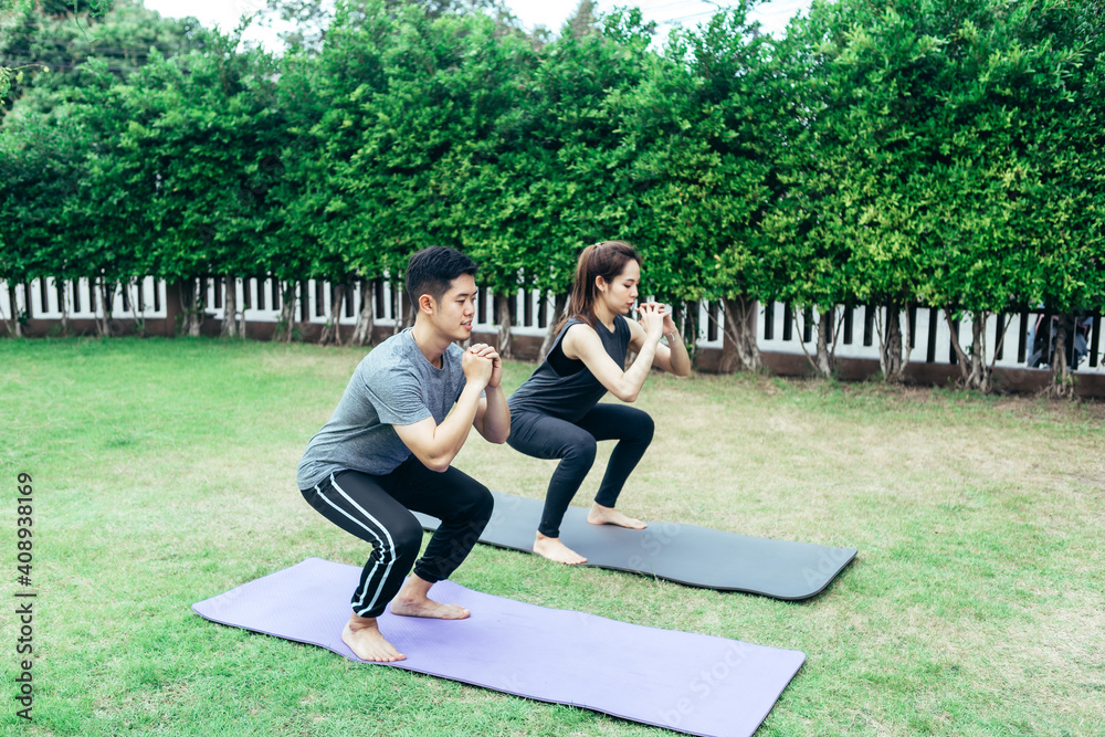 年轻的亚洲夫妇在花园里练习瑜伽。夏日早晨