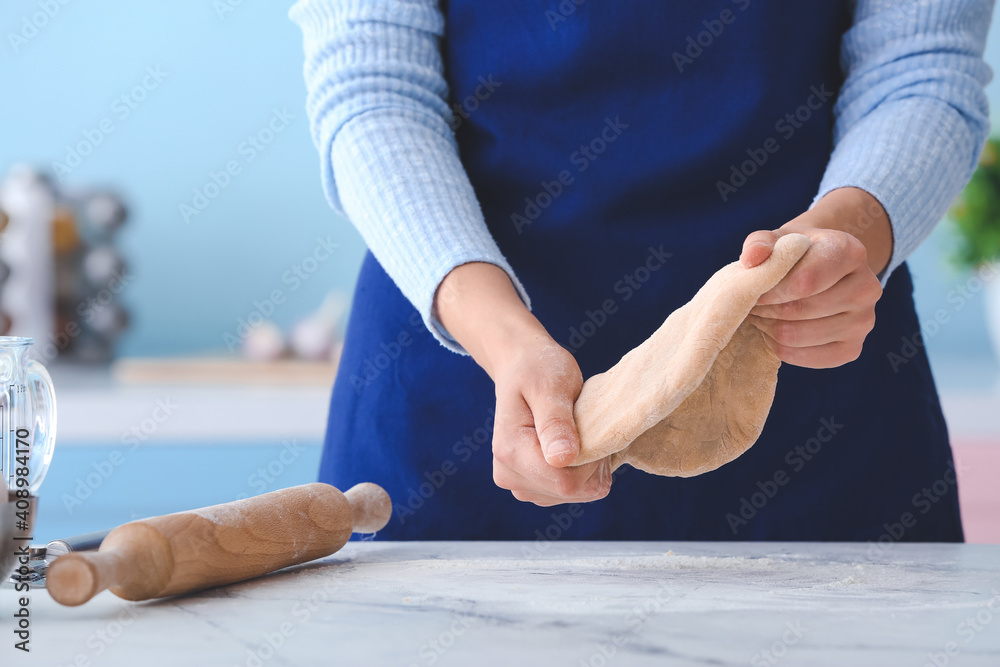 Woman making dough in kitchen