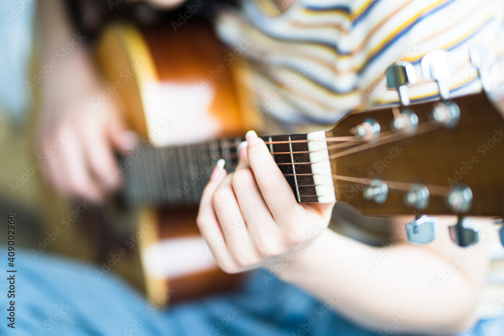 Young Asian girl is practicing guitar at home and composing music