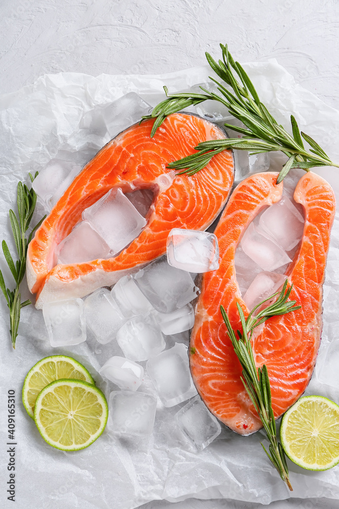 Raw salmon steaks, ice cubes and lime on light background