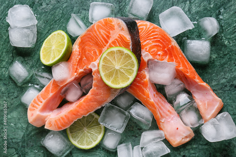 Raw salmon steaks, lemon and ice cubes on color background