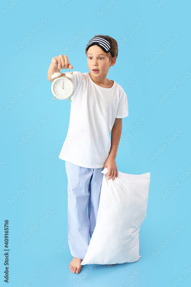 Emotional little boy with alarm clock on color background