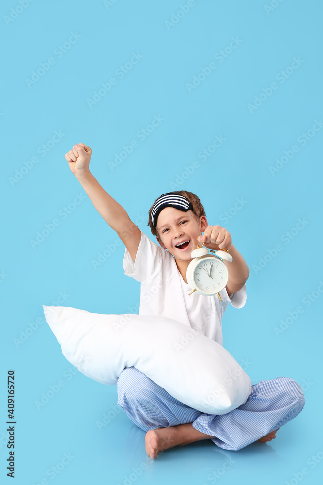 Happy little boy with alarm clock on color background