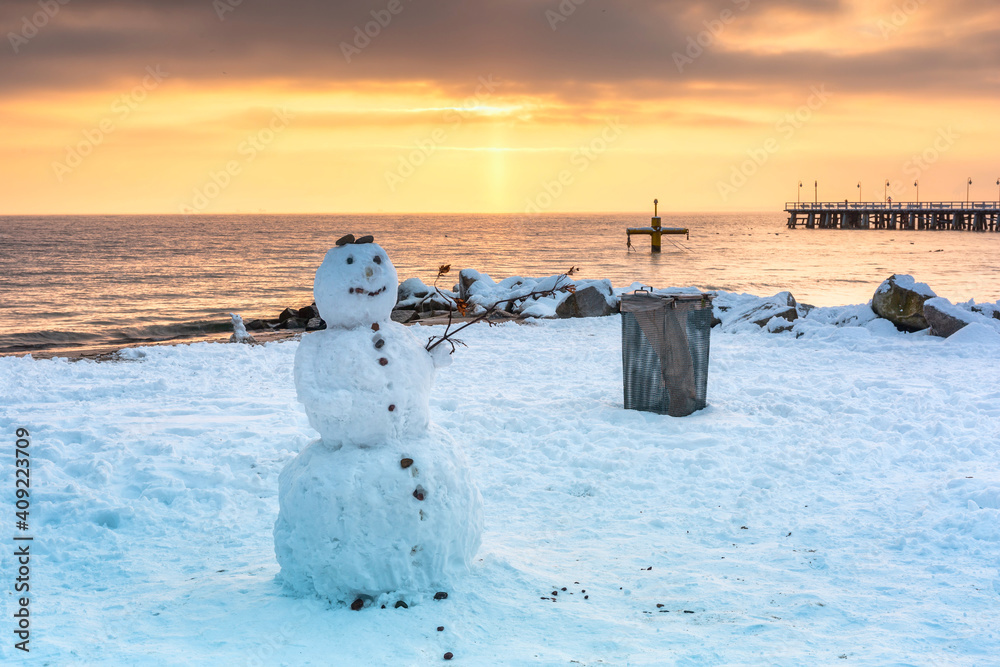 Snowman on the beach of the Baltic Sea in winter at sunrise, Gdynia Orłowo. Poland.