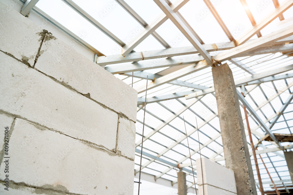 Aerated brick wall and steel roof frame in the construction site,Construction concept.