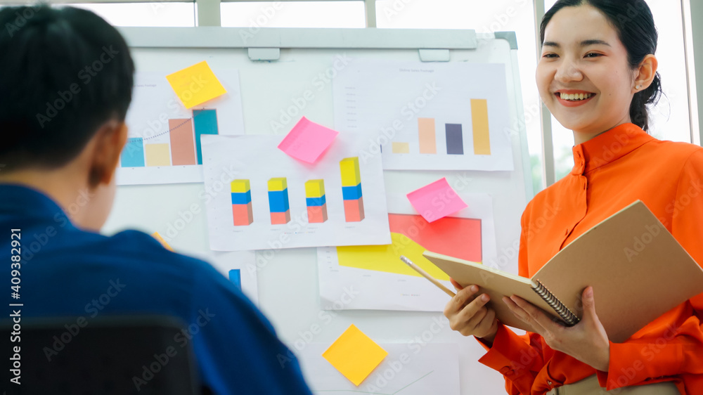 Young woman explains business data on white board in casual office room . The confident Asian busine