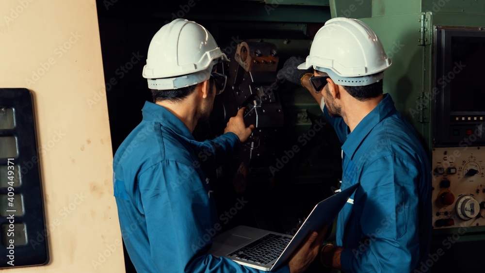 Group of skillful factory workers using machine equipment in workshop . Industry and engineering peo