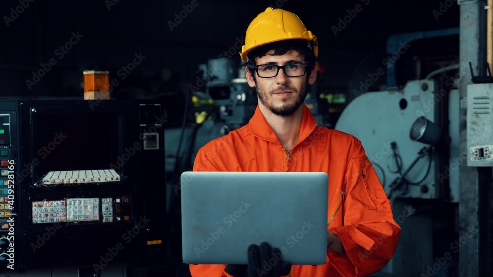 Skillful factory worker working with laptop computer to do procedure checklist . Factory production 