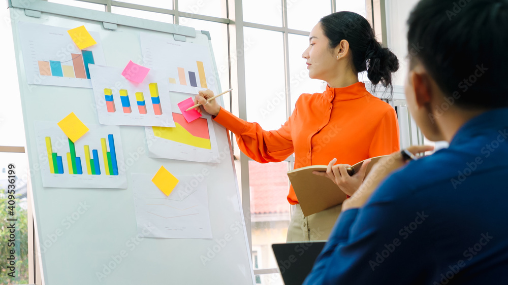 Young woman explains business data on white board in casual office room . The confident Asian busine