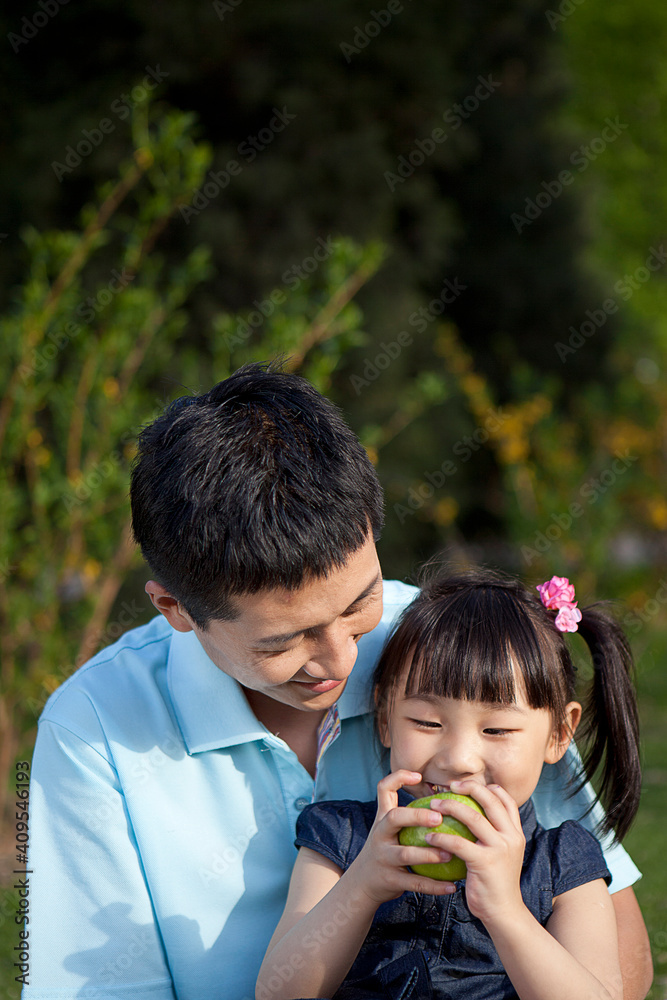 女孩和父亲一起在户外吃水果