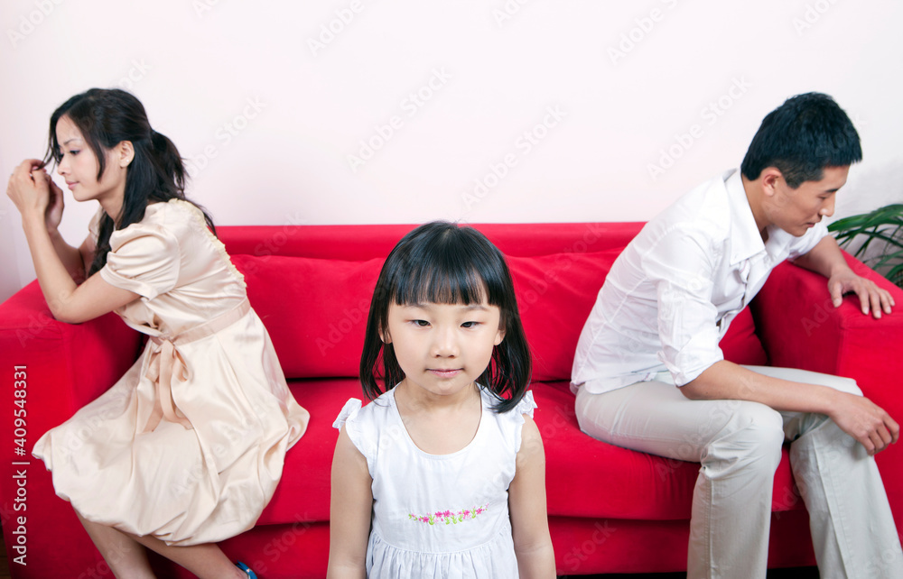 Girls standing,her hostile parents sitting on sofa