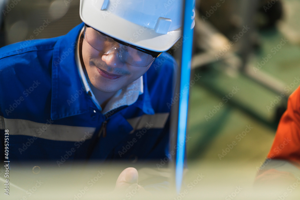 Male Asian engineer professional  having a discussion standing by the machine in the factory ,two as