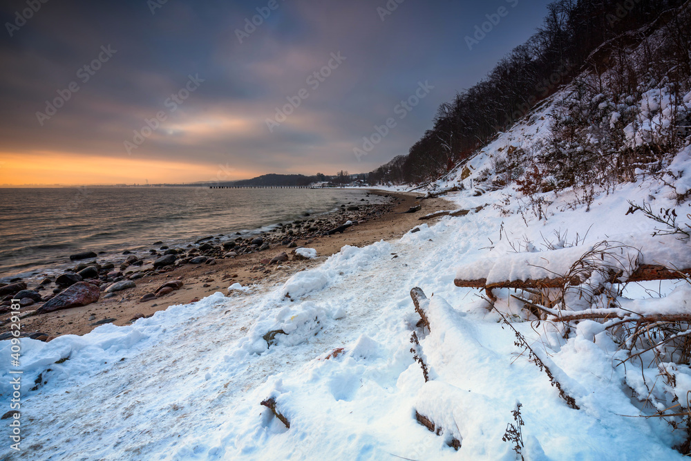 Snowy beach in Gdynia Orlowo at sunrise, Baltic Sea. Poland