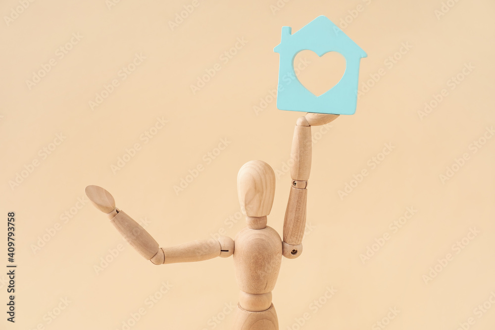 Wooden mannequin with figure of house on color background