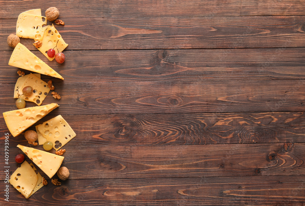 Composition with pieces of tasty cheese and grapes on wooden background