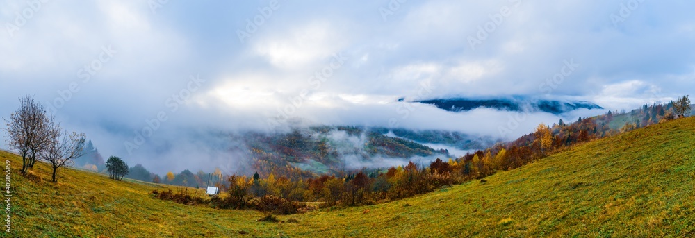 Colorful forests in the warm Carpathian mountains covered with thick gray fog