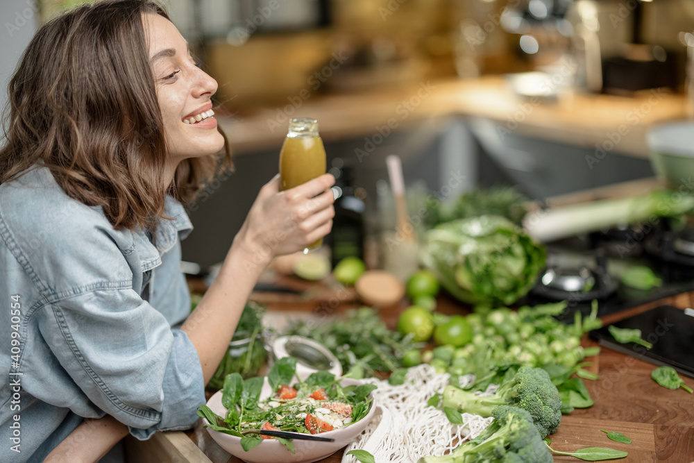 漂亮年轻女人在厨房享用健康清洁食物的个人资料。喝一杯绿色的