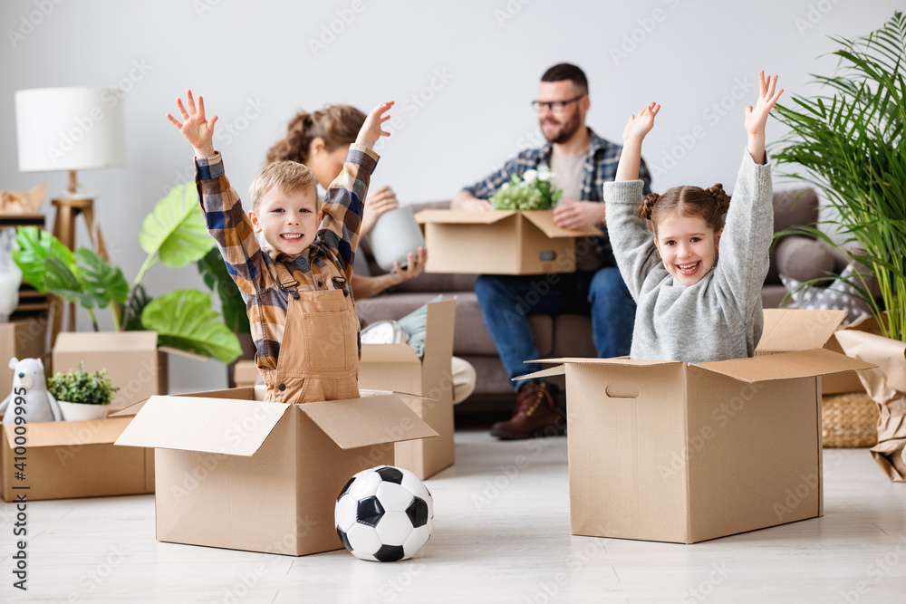 Delighted family: playful siblings sitting in carton boxes with raised arms and enjoying relocation 