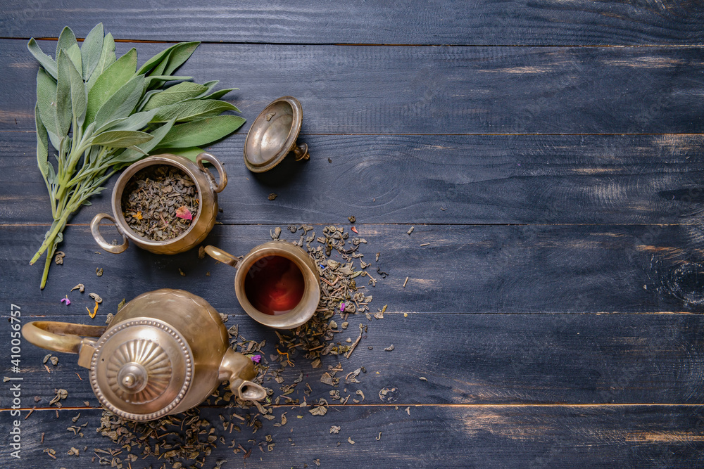 Teapot and dry tea leaves on wooden background