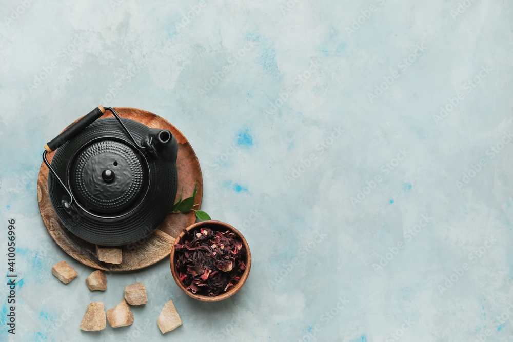 Composition with teapot and dry tea leaves in bowl on color background