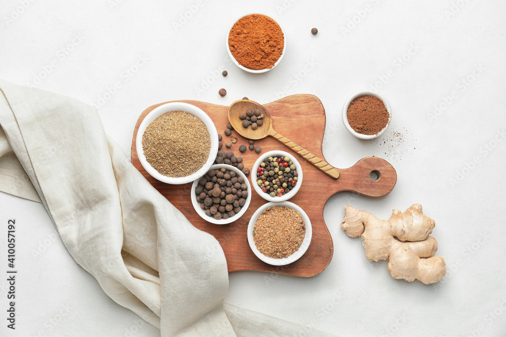 Board with different spices on white background