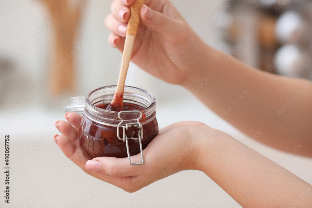 Woman with jar of delicious homemade plum jam at home