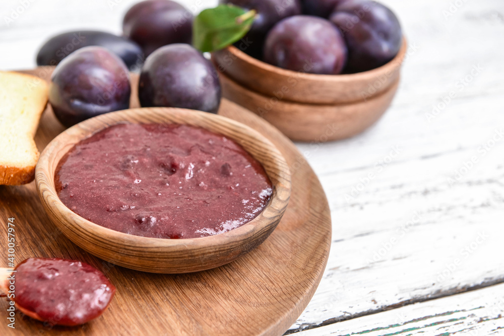 Bowl with delicious homemade plum jam on wooden background