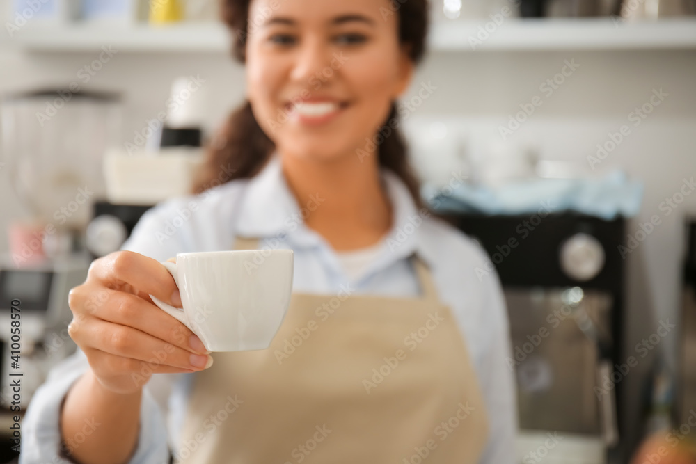 Young barista with cup of hot espresso in cafe, closeup