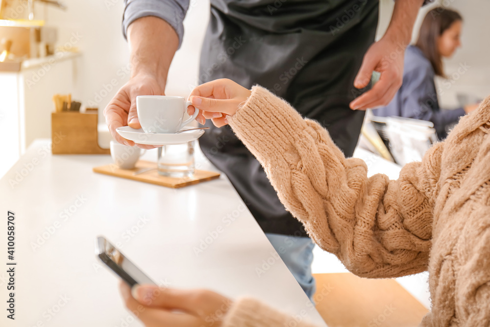 Barista bringing hot espresso for visitor in cafe