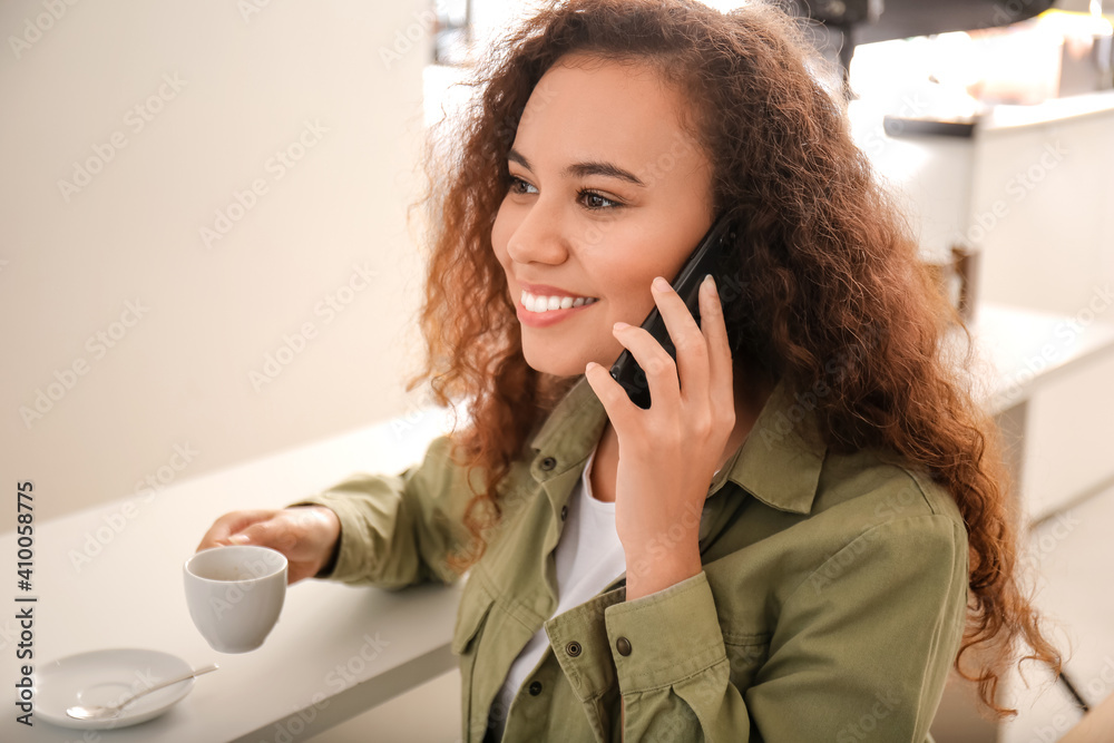 Beautiful woman with mobile phone and cup of hot espresso in cafe