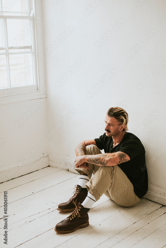 Alternative man sitting on a white wooden floor