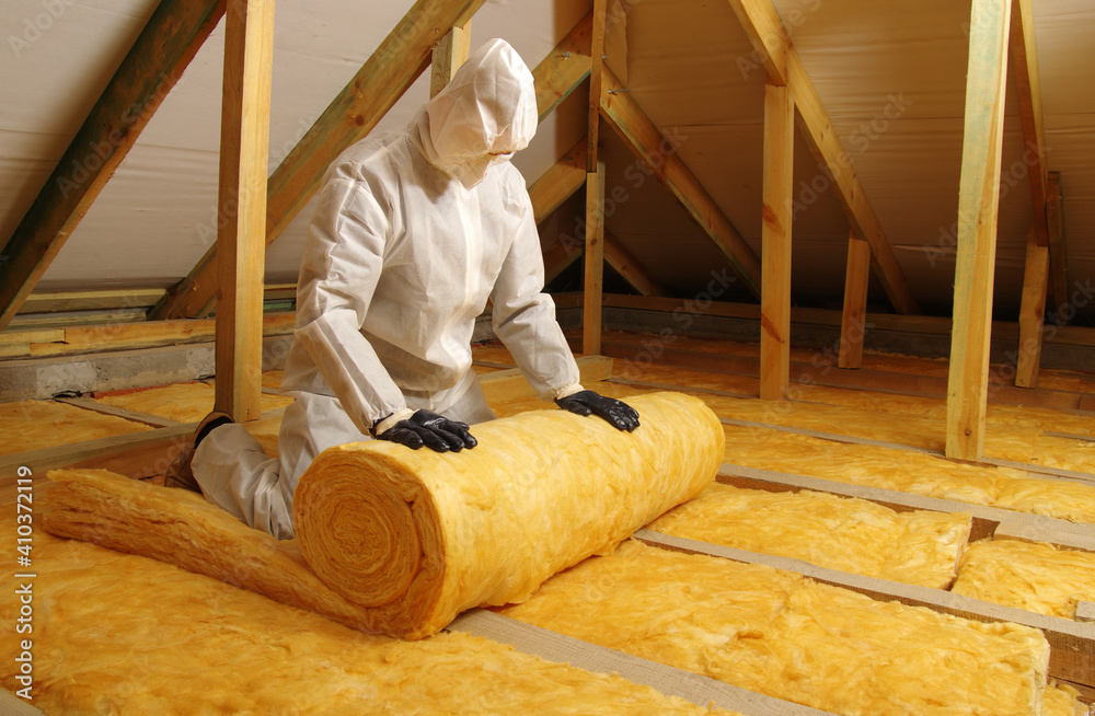 Man installing thermal insulation layer under the roof