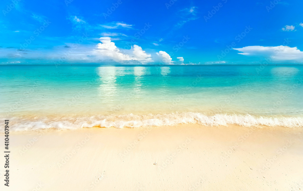 热带海滩的美丽背景图片。白色泡沫的浅海浪。蓝色的夏日天空，白色