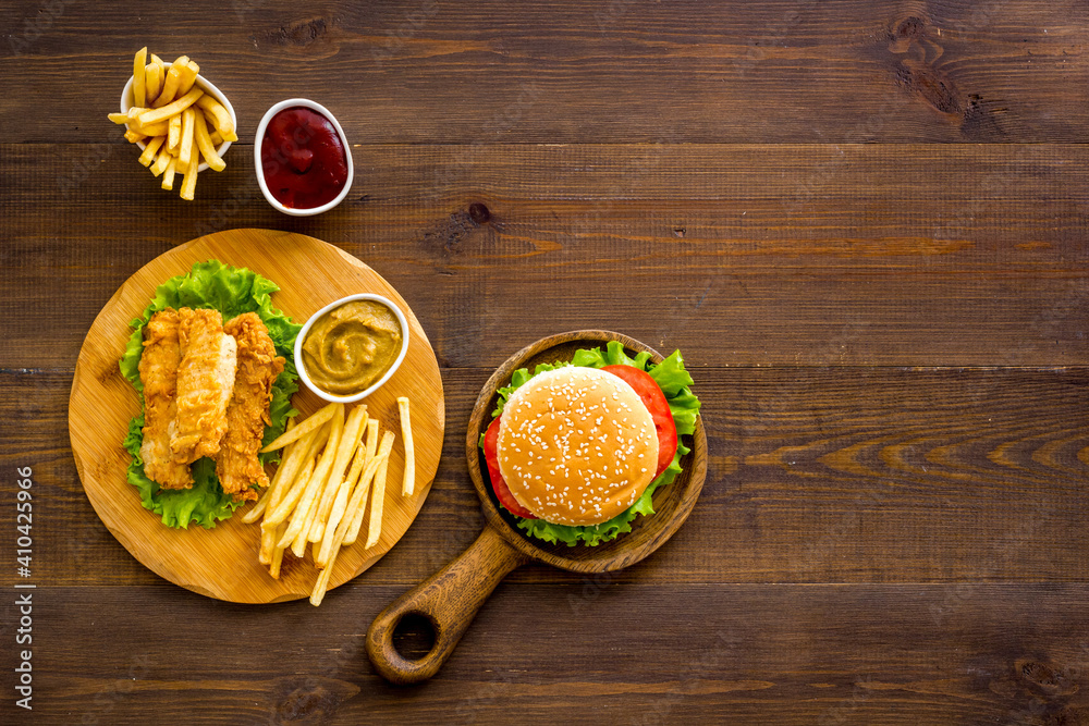 Top view of delicious burgers on on wooden board. Fried potatoes and chicken