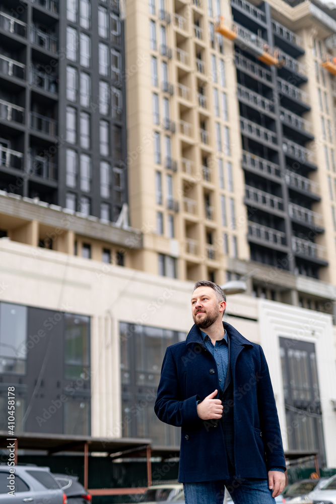 Portrait of a handsome young businessman standing outside a modern building. View from below.