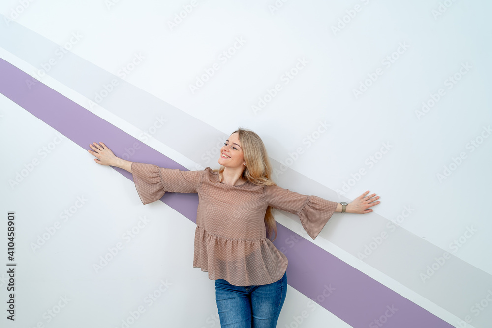 Cute woman with streched hands is posing to the camera in light pink blouse and blue jeans. Closeup.