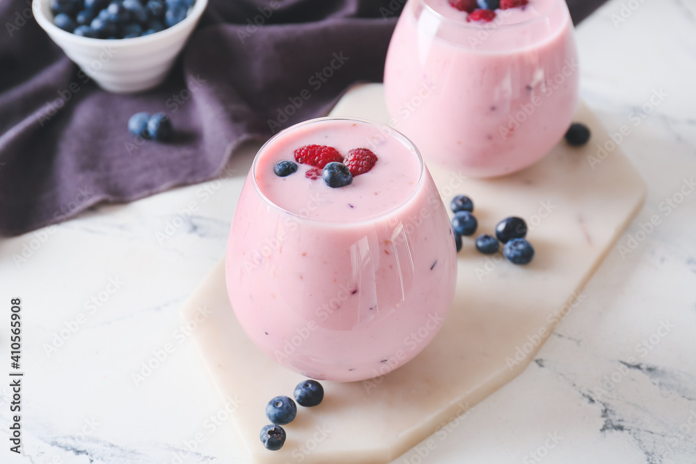 Glasses of tasty smoothie with blueberry and raspberry on light background