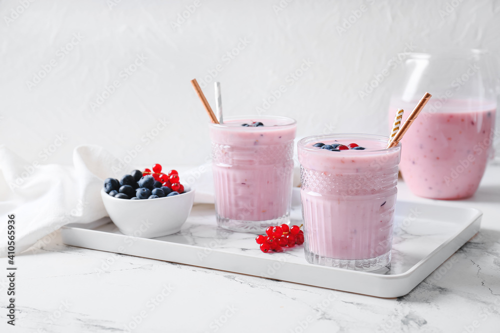 Glasses of delicious smoothie with blueberry and cranberry on light background