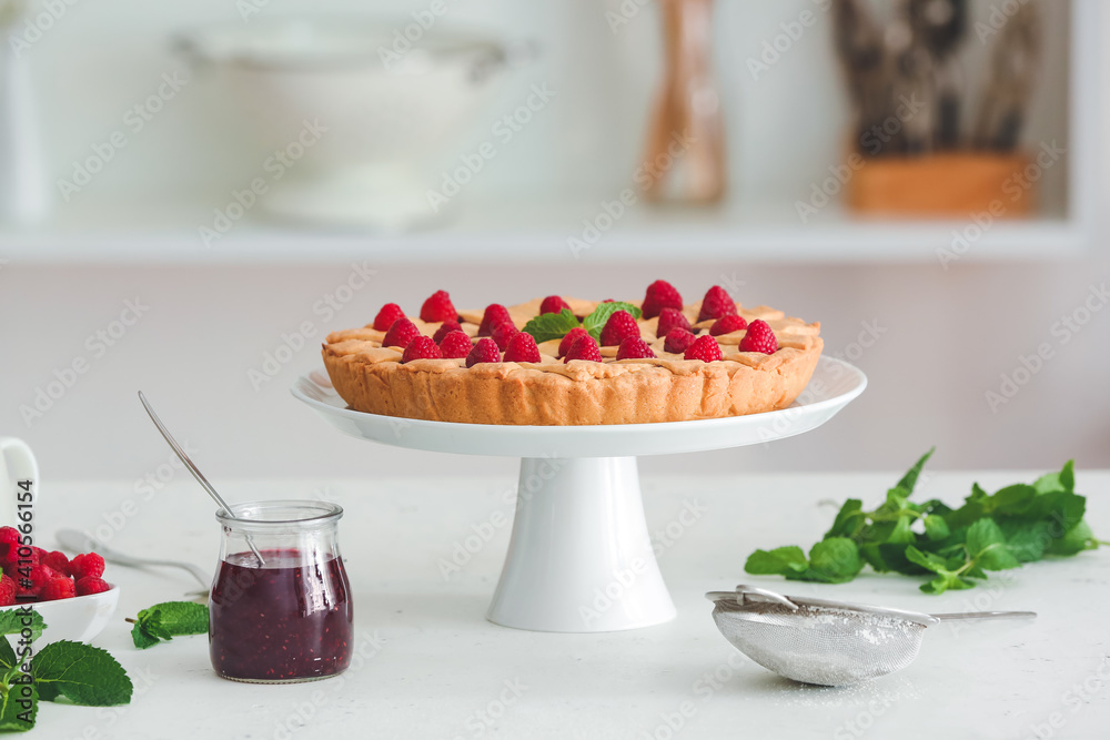 Dessert stand with tasty raspberry pie and jam on table in kitchen