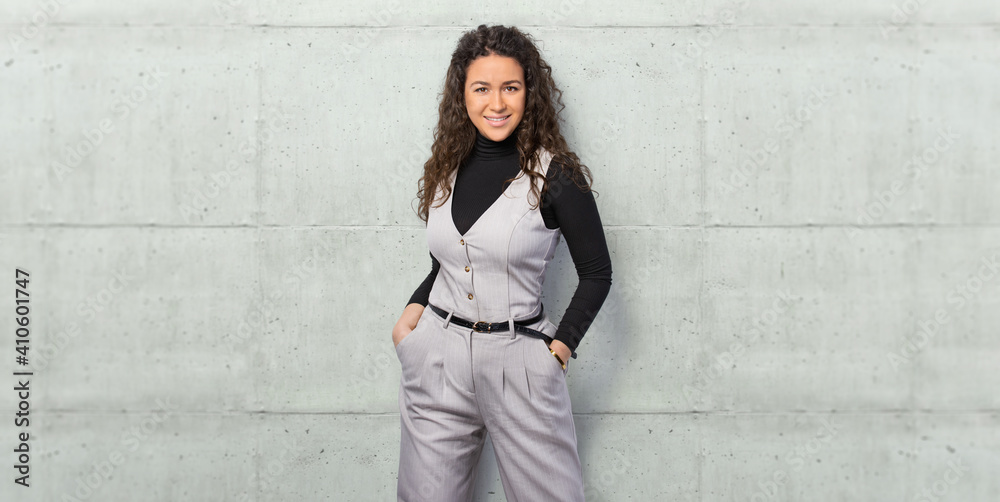 Happy young business woman posing isolated over grey wall background.