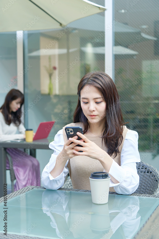 カフェテラスでスマホを使う女性