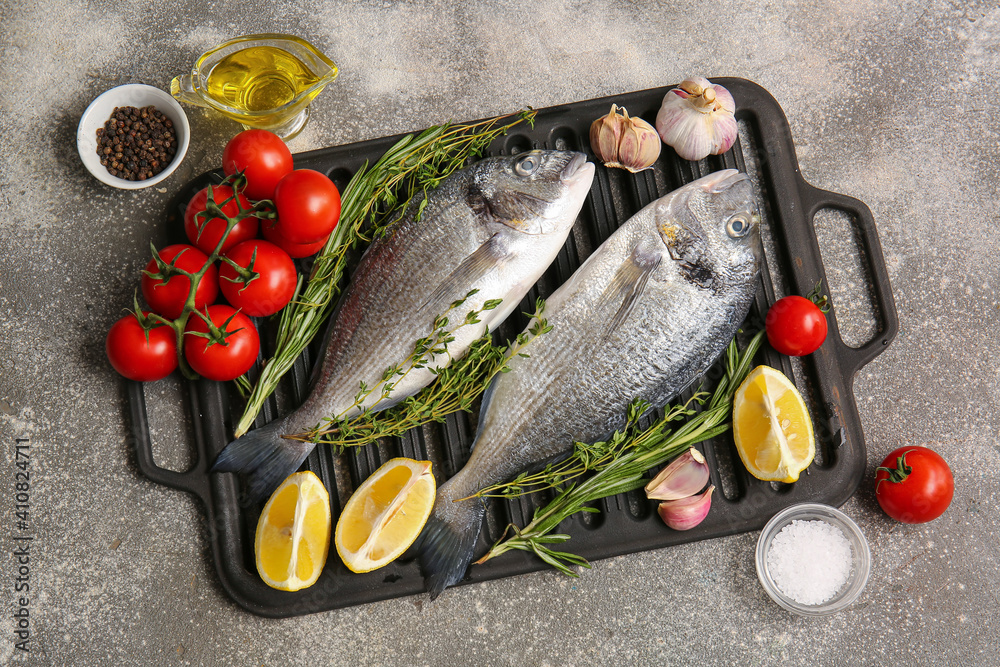 Raw dorado fish with ingredients on gray background