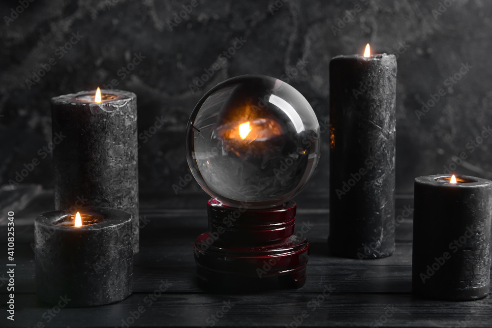 Crystal ball of fortune teller and candles on dark background