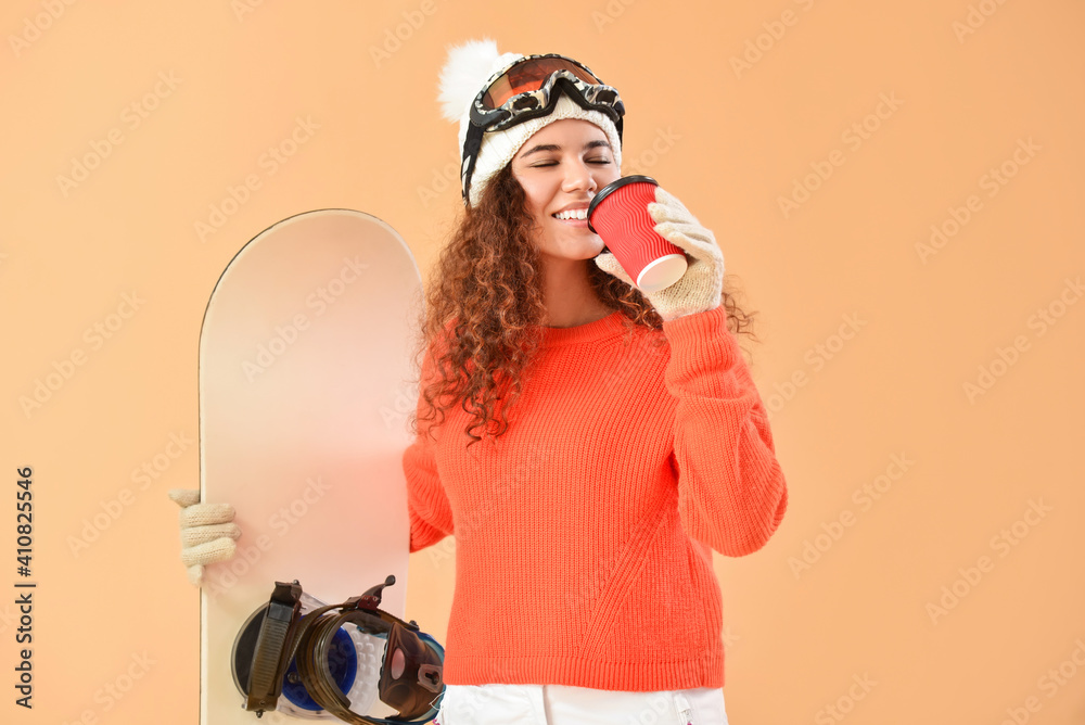 Female snowboarder drinking coffee on color background