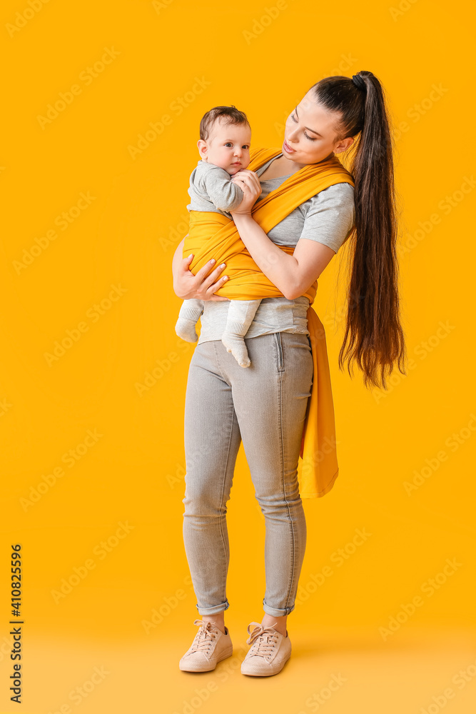 Young mother with little baby in sling on color background