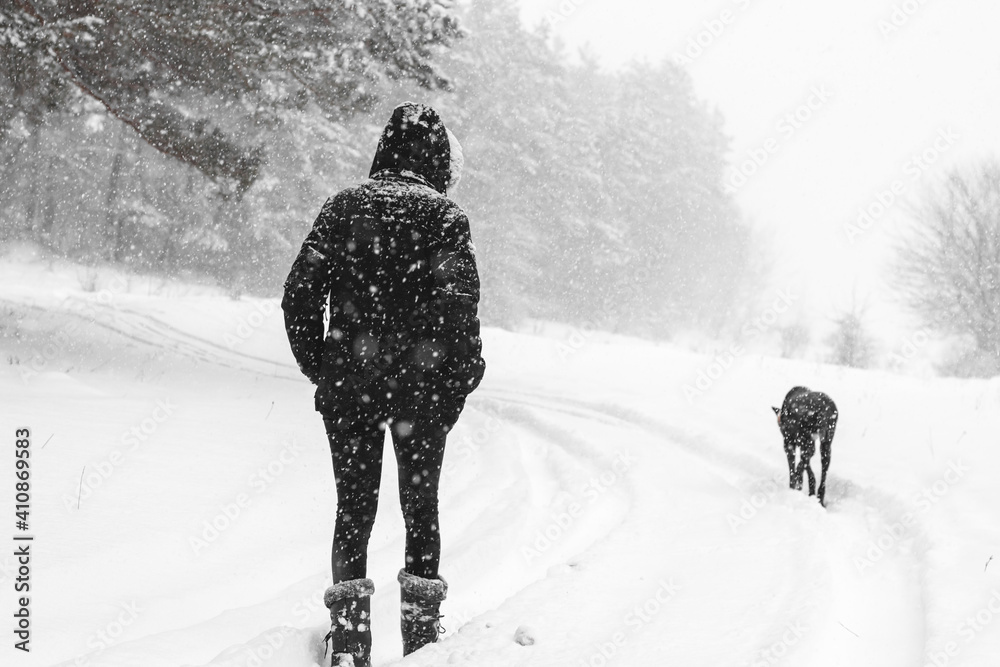 Girl walks with dog during heavy snow