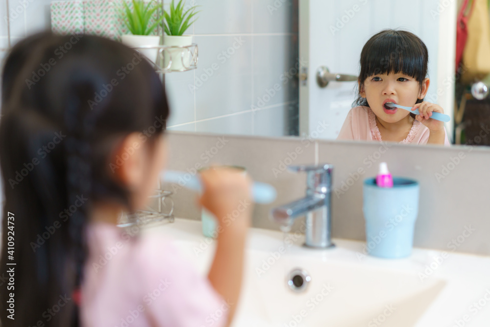 Asian cute child girl or kid brushing her teeth by toothbrush in the bathroom. Dental hygiene Health